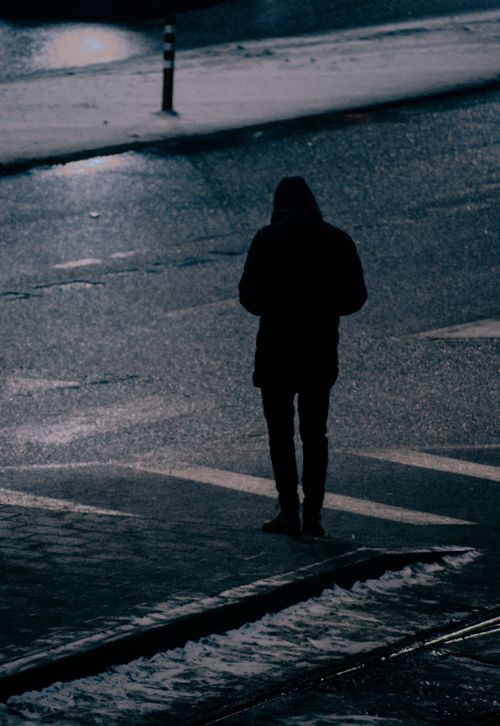 Free Moody silhouette of a person standing on an empty street at night, conveying solitude. Stock Photo