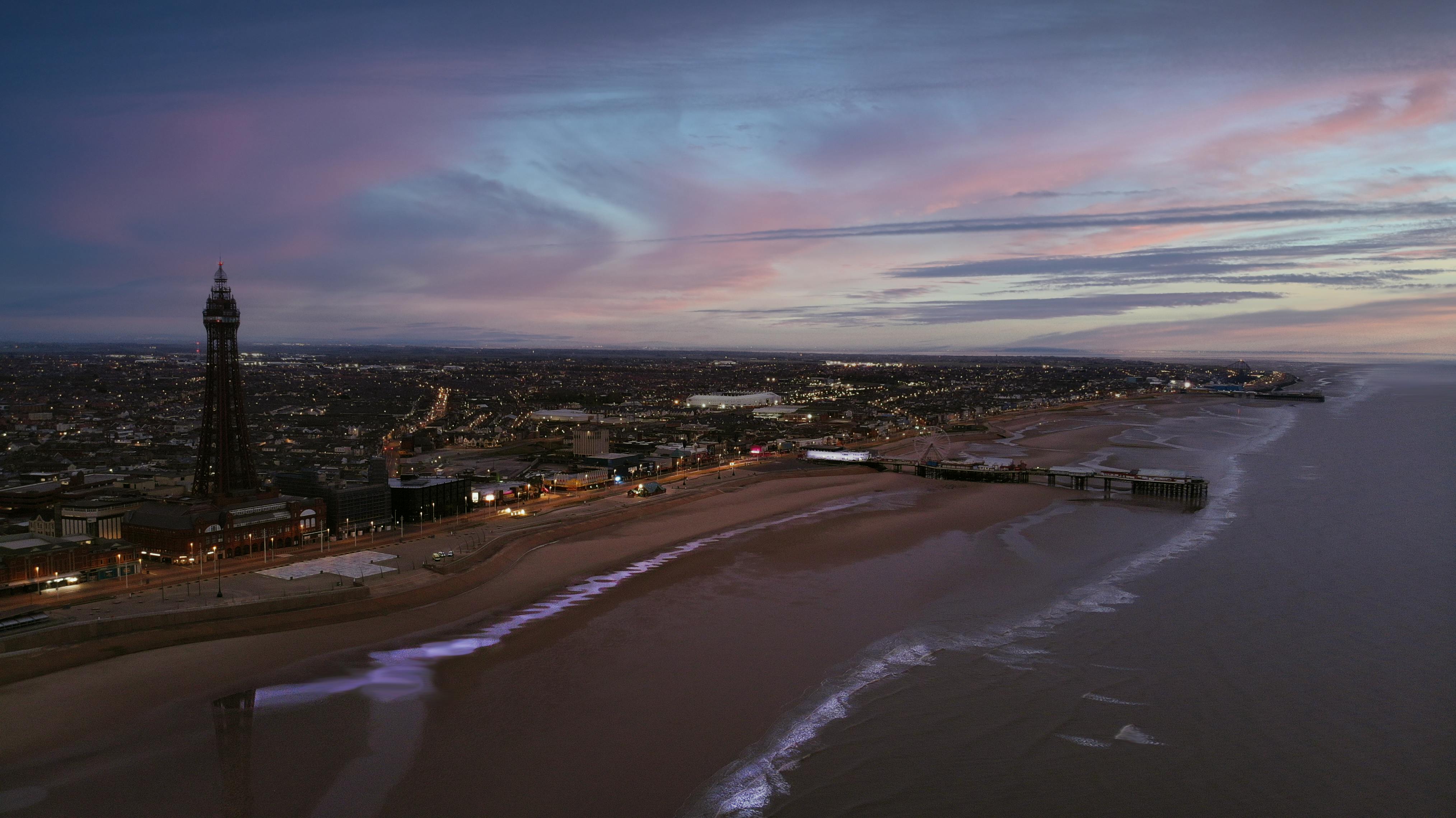 Stunning aerial view of a coastal city with iconic tower at sunset.