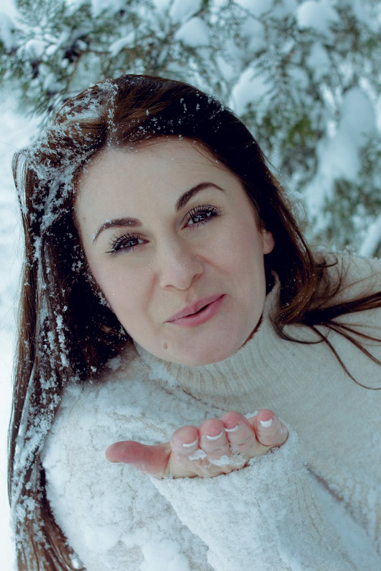 Woman In White Turtleneck Sweater Blowing Snow From Her Hand 