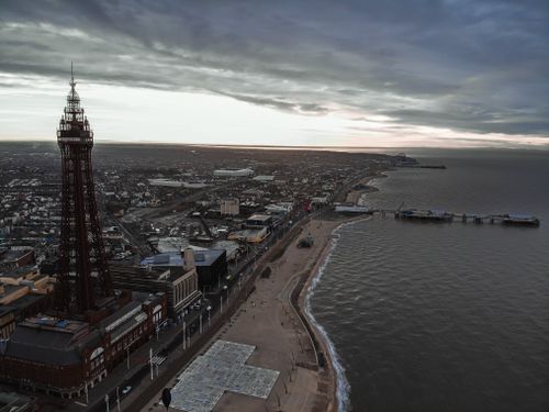 Free A stunning aerial shot showcasing Blackpool Tower and the North Pier along the coastline at dawn. Stock Photo