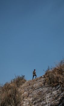 A lone man climbs a mountain in Peru under a clear blue sky, capturing the spirit of adventure.