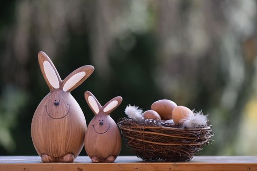 Charming wooden bunny figurines beside a nest of eggs, perfect for Easter decor.