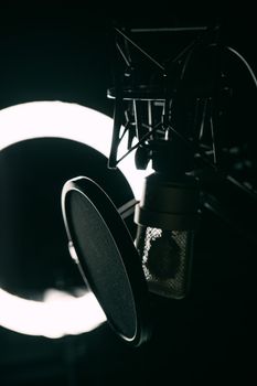 Close-up of a condenser microphone and ring light setup in a recording studio.