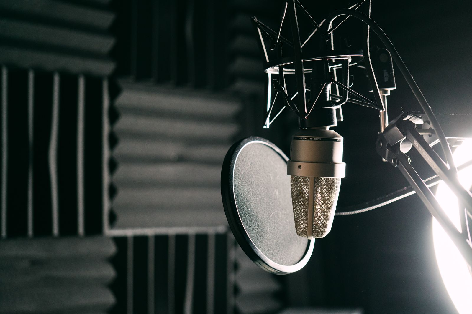 Close-up of a condenser microphone with pop filter in a soundproof studio