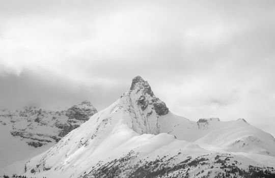 A breathtaking snow-covered mountain peak in British Columbia under a cloudy sky.