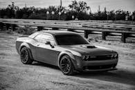 Grayscale Photo of Dodge Challenger Parked on Unpaved Road