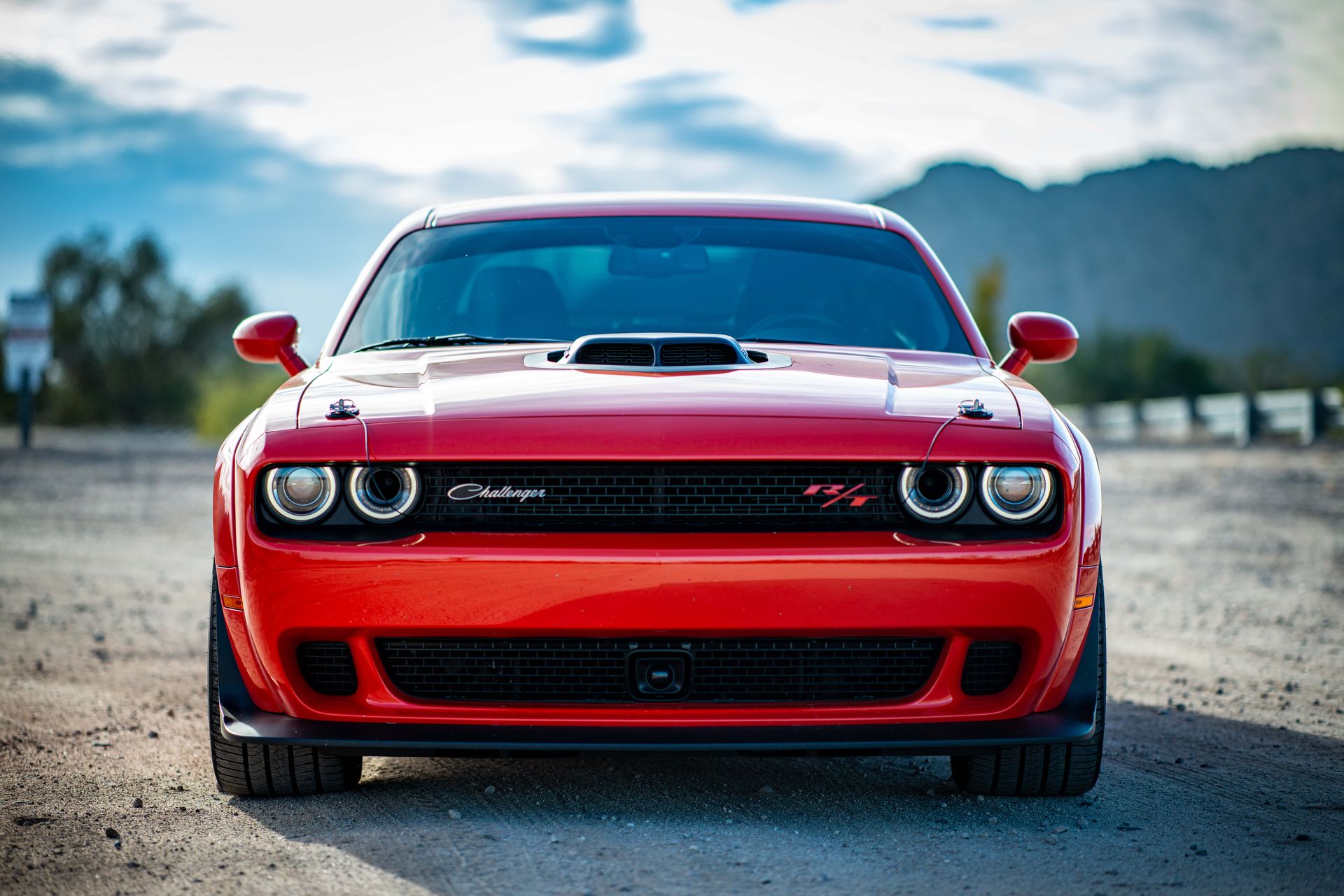 Red Dodge Challenger with Hood Scoop Parked on Unpaved Road