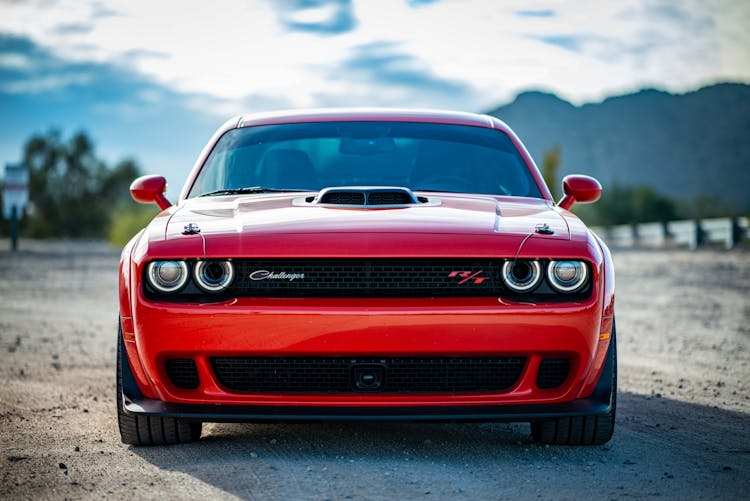 Red Dodge Challenger With Hood Scoop Parked On Unpaved Road