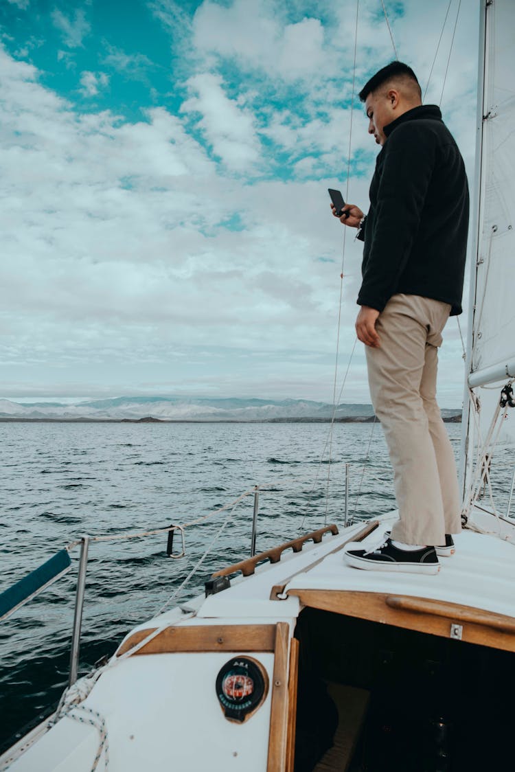 Man Standing On The Boat And Using His Smartphone