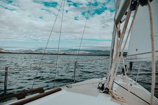 View from a sailboat deck with mountains in the distance on a clear day.