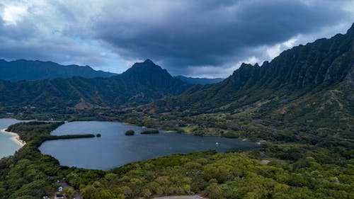 Green Mountains Near Body of Water Under Cloudy Sky