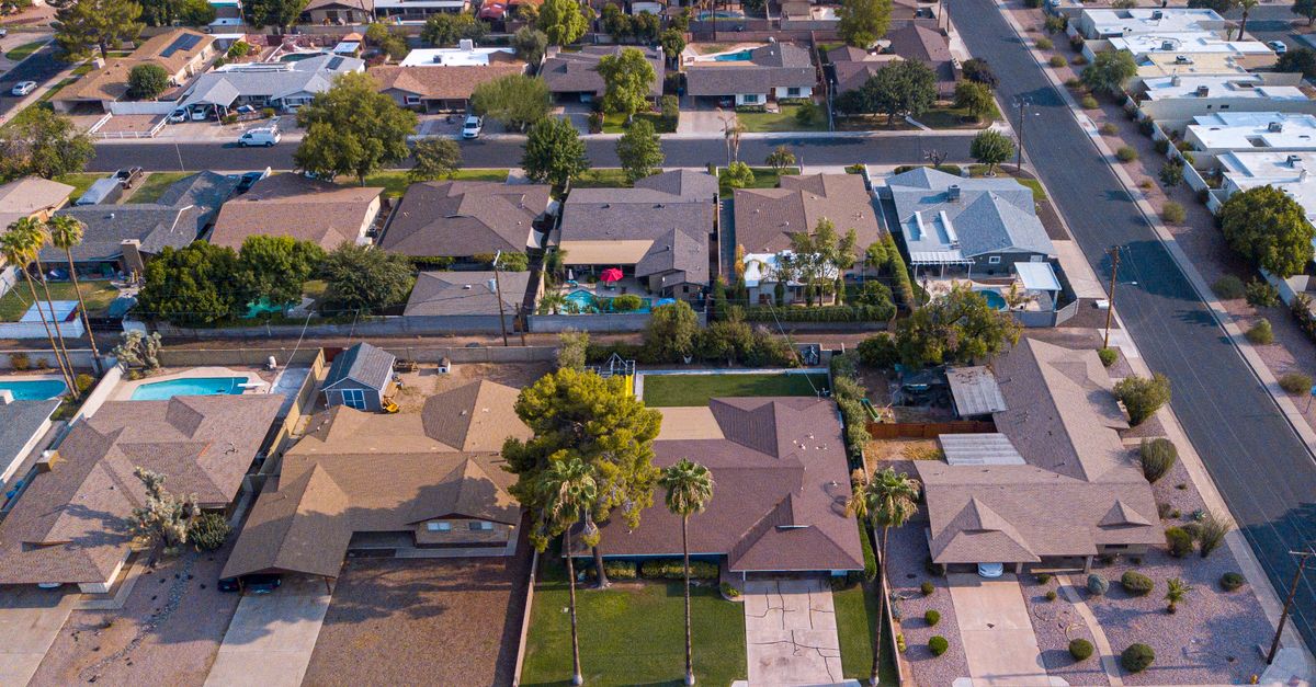 High-angle view of suburban houses and streets in a sunny neighborhood.