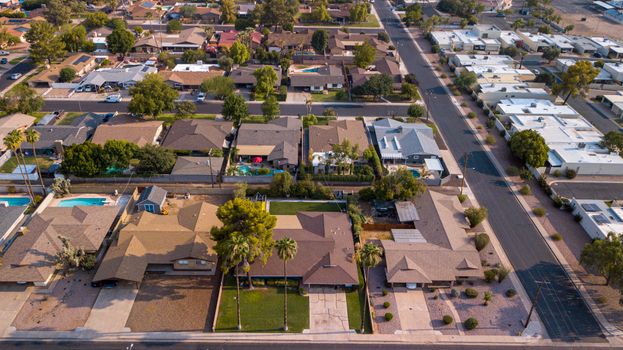 Drone shot of a suburban neighborhood showcasing houses, roads, and lush greenery.