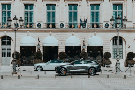 Two luxury cars parked in front of an upscale historical building with classic architecture.