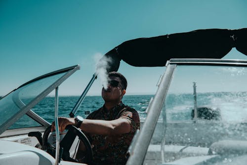 A Man Driving a Yacht while Smoking