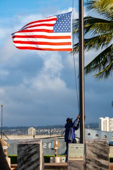 A man raises the American flag outdoors, showcasing national pride.