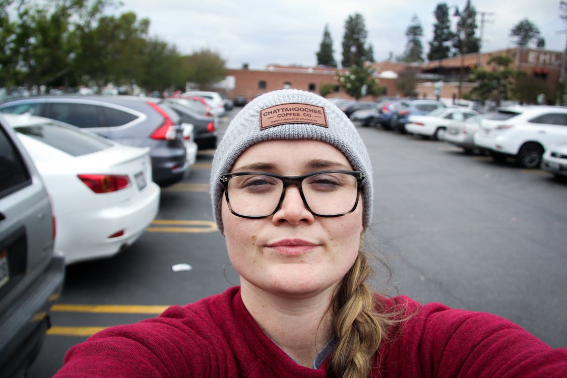 Free Женщина фотографирует себя возле припаркованных автомобилей Stock Photo