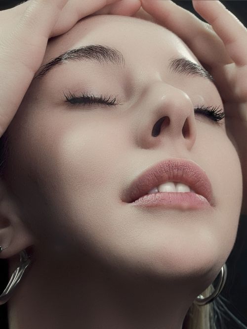 Free A serene close-up of a woman with closed eyes and delicate makeup in a relaxed pose. Stock Photo