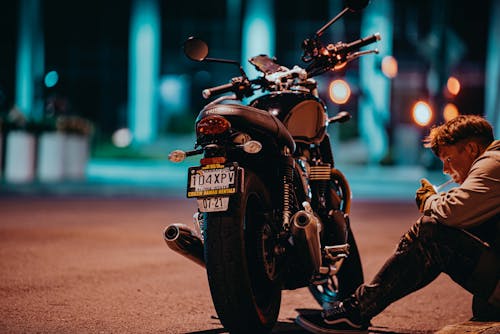 Man Lighting a Cigarette Beside a Motorbike