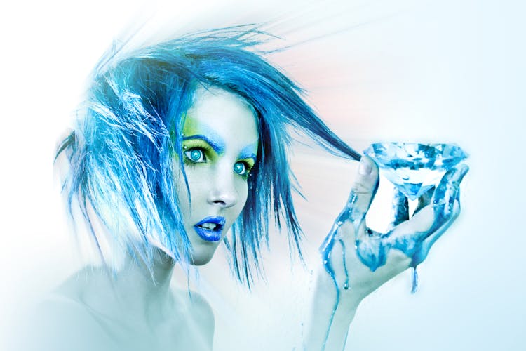 A Woman With Blue Hair Looking At The Diamond She Is Holding