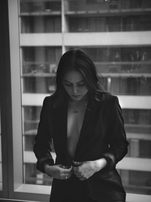 Free Woman in a Blazer Standing by the Window Stock Photo