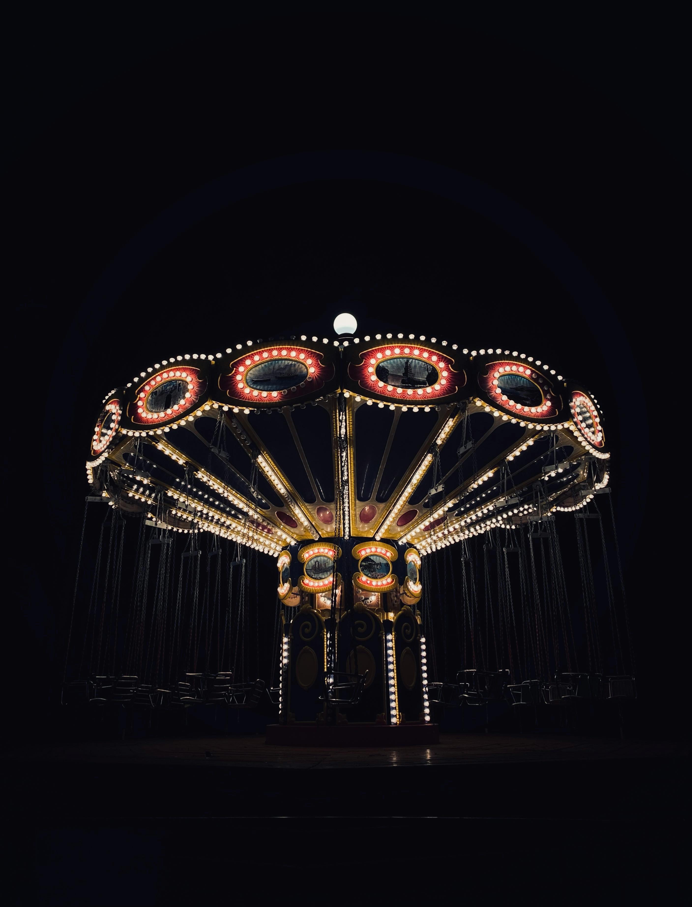 A beautifully lit carousel stands out against the dark night sky, creating a magical atmosphere.