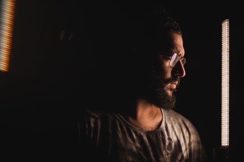 Free Artistic low-light portrait of a bearded man with eyeglasses, illuminated by soft lighting. Stock Photo