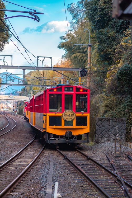 Free Vibrant red and yellow train traveling through lush landscape along a railway track. Stock Photo