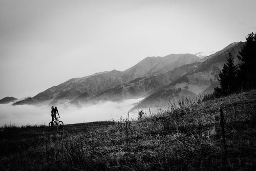 Free Biker rides through a misty mountain landscape, captured in striking black and white. Stock Photo