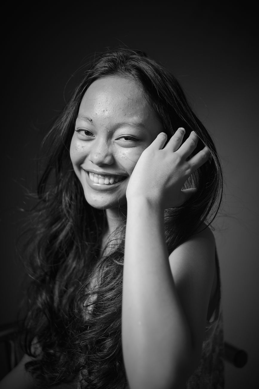 Black and white portrait of a smiling woman with long hair.