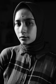 Serene black and white portrait of a Muslim woman wearing a hijab, captured indoors.