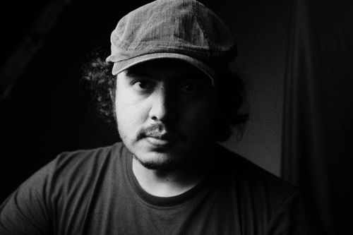 Free Black and white portrait of a man with curly hair wearing a flat cap and serious expression. Stock Photo