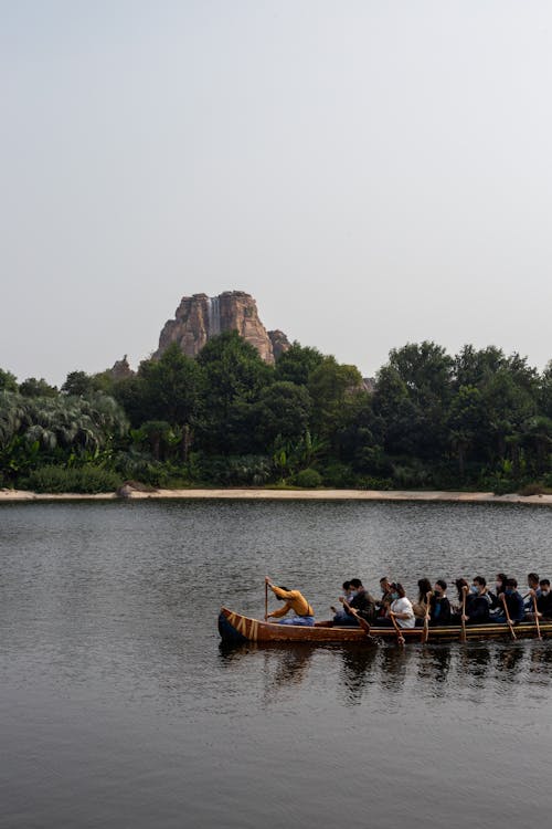 People Riding on a Boat while Paddling Together