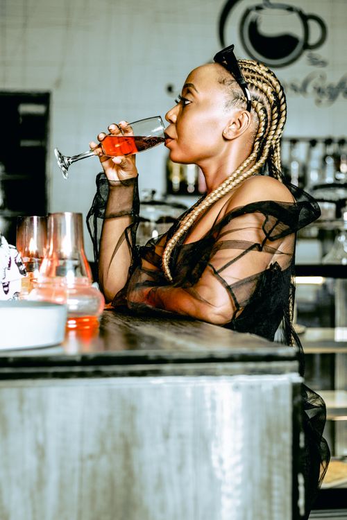 Free A fashionable woman with braided hair enjoys a drink in a chic bar setting. Captured in profile. Stock Photo