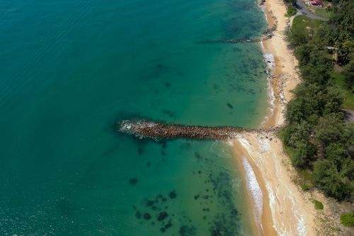 Free A stunning aerial view of a tropical beach with turquoise water and lush greenery, perfect for summer vacations. Stock Photo