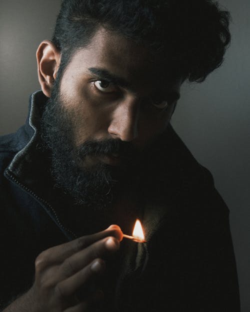 Man with Beard Holding Lit Matchstick