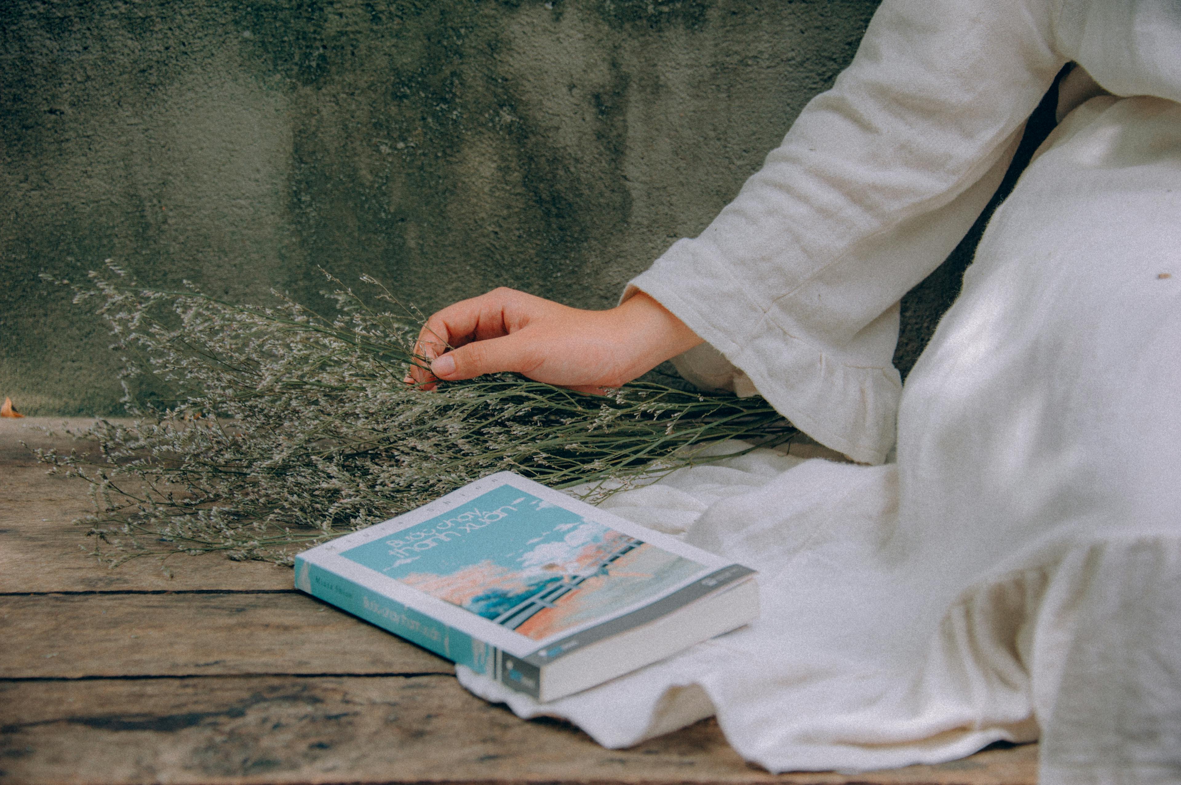 Blue and White Book Beside Woman Wearing White Dress