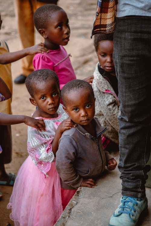 Girl in Pink Dress Standing beside Boy in Brown Jacket