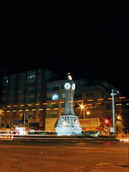 Nighttime cityscape featuring an illuminated clock tower with light trails.