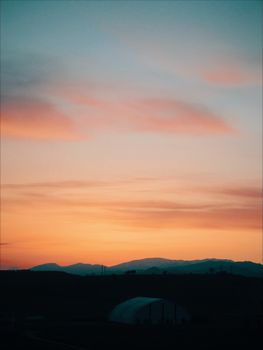 A stunning sunset hues the sky above a serene mountain range, offering a peaceful silhouette.