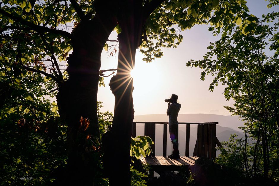 Silhouette of a person photographing the sunset on a wooden bridge in Vălișoara, Romania.