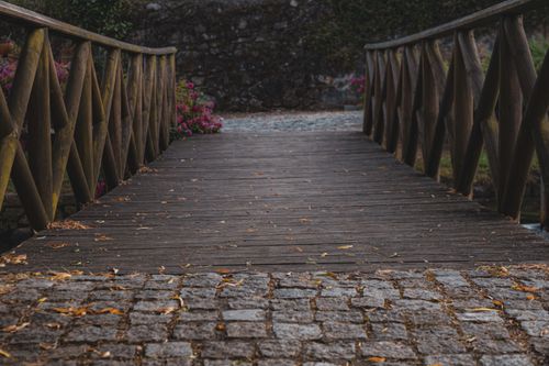 Free Charming rustic wooden bridge and cobblestone pathway in a lush garden setting. Stock Photo
