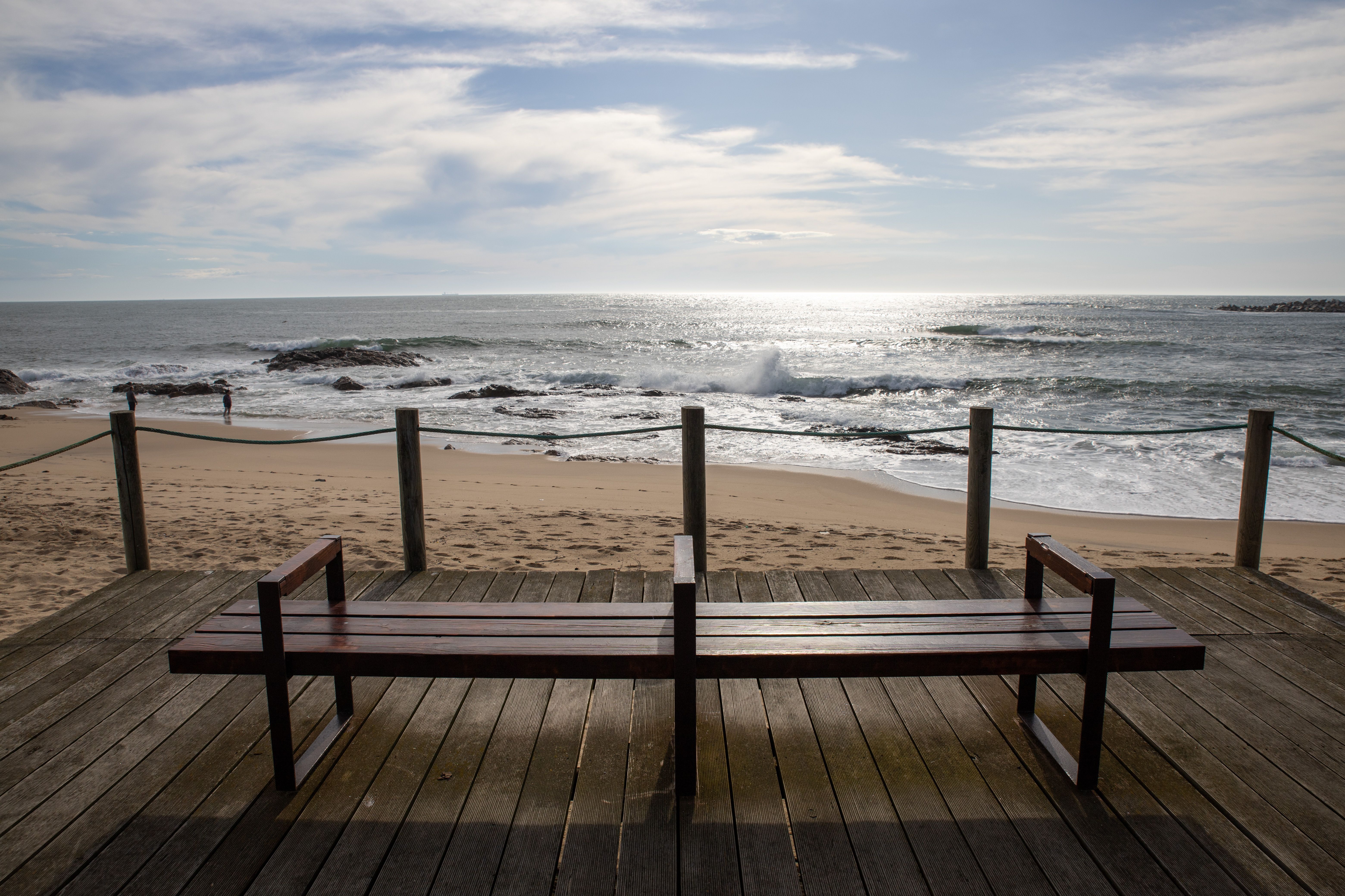 Wide view of Lavra's beach with a wooden bench and scenic ocean horizon.
