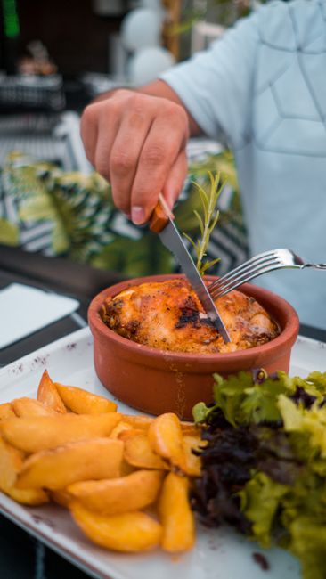 A baking dish of poppy seed chicken casserole with a golden, buttery cracker topping and a serving spooned out over rice, revealing the creamy shredded chicken filling studded with poppy seeds.
