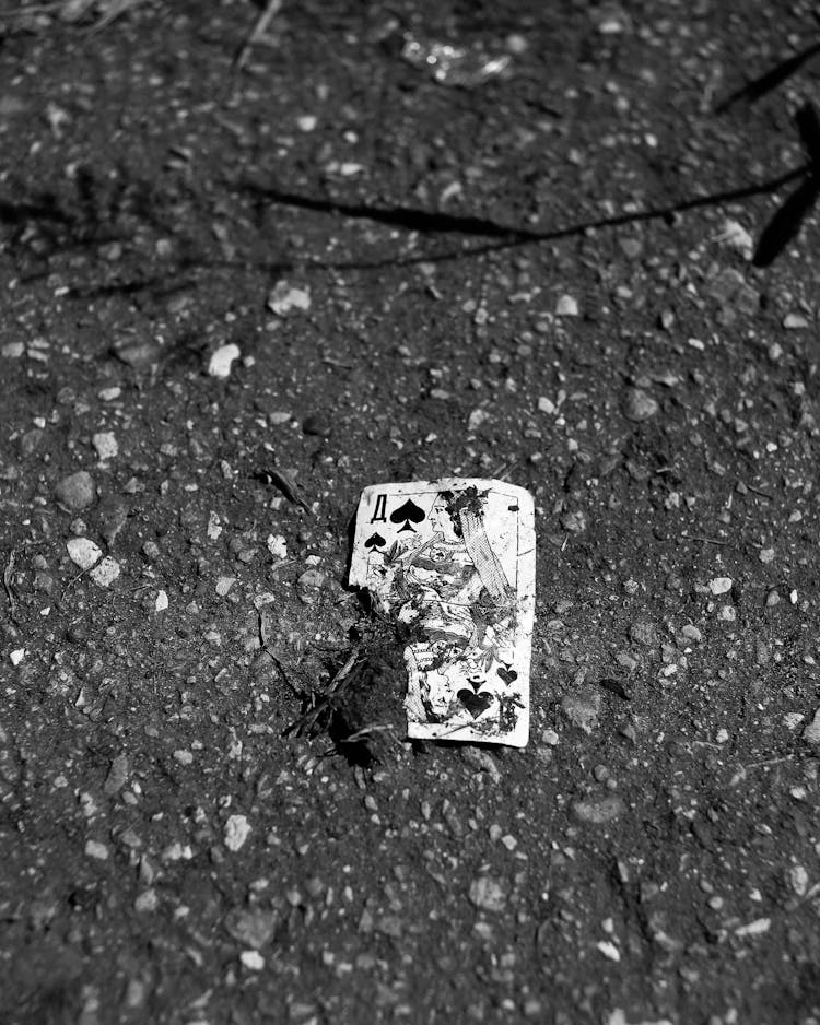 Grayscale Photo Of A Broken Poker Card On The Ground