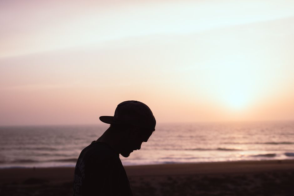 A serene silhouette of a man wearing a cap at Peniche beach during sunset, reflecting tranquility.