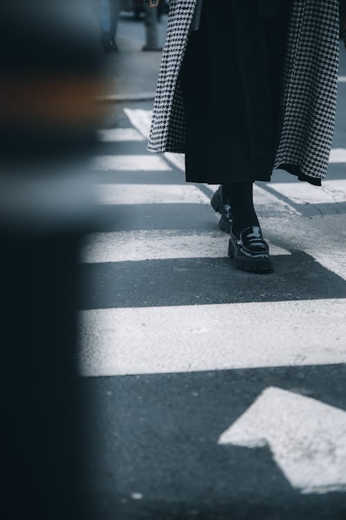 Person in Black and White Polka Dot Skirt and Black Shoes Standing on Gray Concrete Road