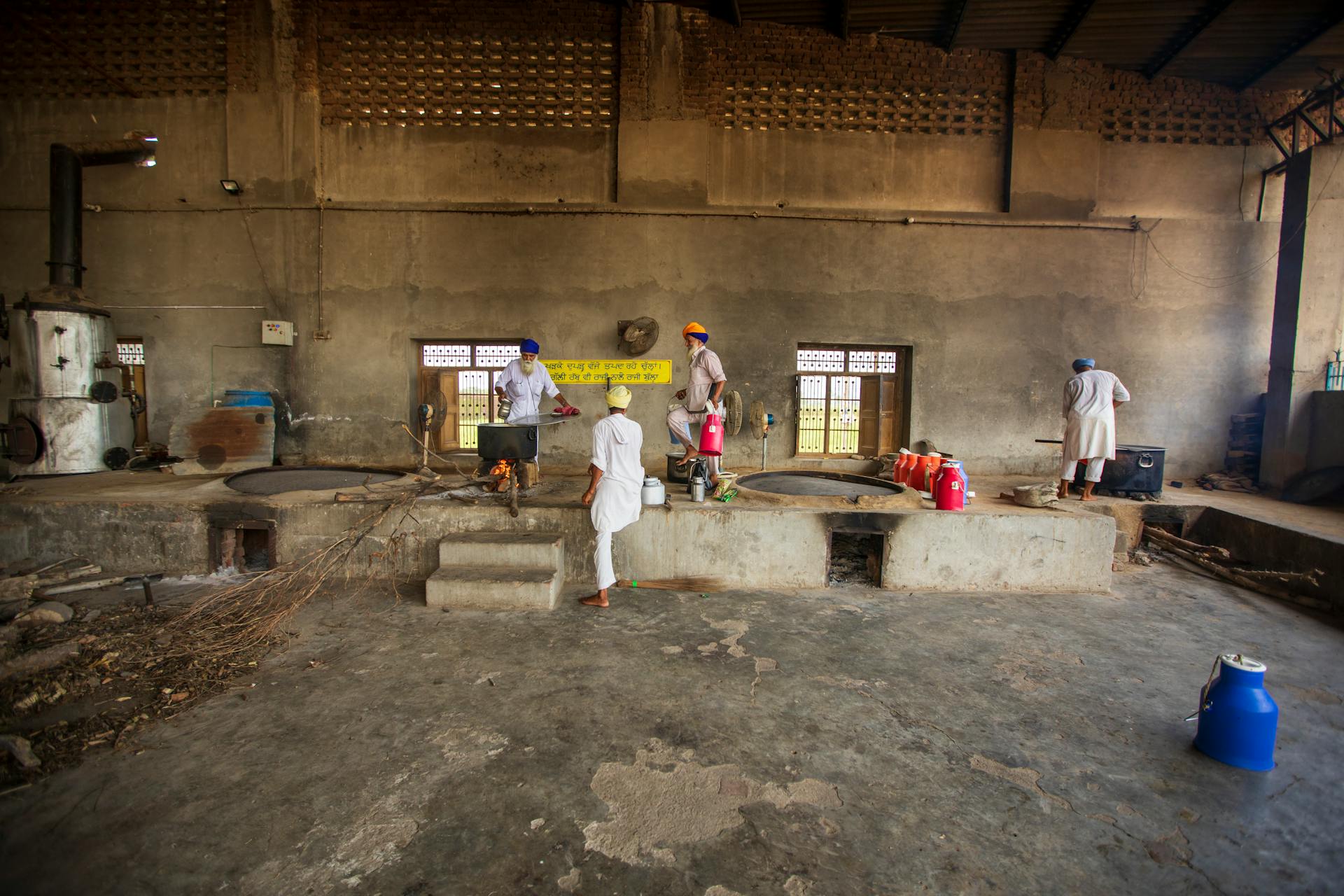 Workers in an Indian industrial interior wearing traditional turbans, focused on tasks.