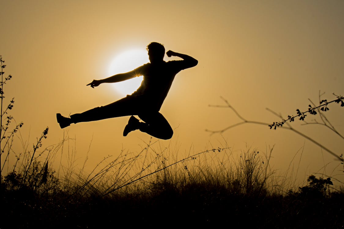 免费 男人在日落时做踢跳的剪影 素材图片