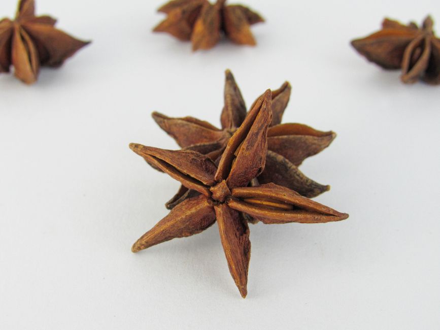 Fotomural Primer plano de anís estrellado sobre superficie blanca, ideal para temas culinarios.